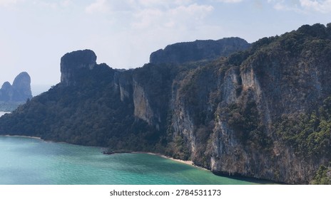 Dramatic limestone cliffs covered in lush vegetation overlook the turquoise waters of the Andaman Sea.