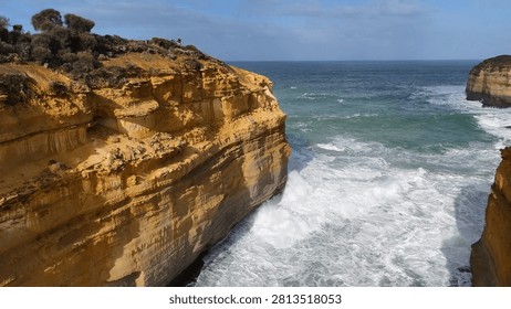 Dramatic limestone cliffs meet churning ocean waves at Loch Ard Gorge in Victoria, Australia.