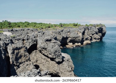Dramatic limestone cliffs meet turquoise ocean waters under a clear blue sky, perfect for breathtaking natural landscapes and travel.