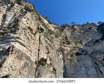 Dramatic limestone cliffs rising under clear blue sky, natural rock formations with layered textures, ideal for travel, adventure and scenic landscape themes.