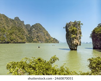 A dramatic limestone rock formation rising from the turquoise waters of Phang Nga Bay in Thailand. This iconic landmark is a popular tourist destination, known for its role in the James Bond movie.  - Powered by Shutterstock