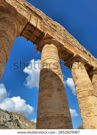 Dramatic low angle diagonal view of ancient Doric stone columns and entablature at the Temple of Segesta, Sicily, Italy.
