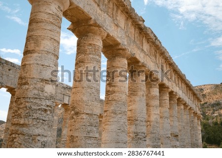 Dramatic low angle perspective view of the long Doric colonnade and architrave of ancient Greek temple in Segesta, Sicily, Italy