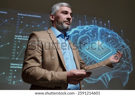 Dramatic low angle portrait of mature neurology expert giving presentation on brain implants gesturing at holographic projection copy space