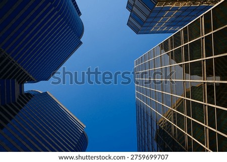 Dramatic low angle upward view of multiple blue glass skyscrapers converging against clear sky