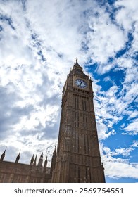 Dramatic low angle view of Big Ben Clock Tower at Westminster Palace in London, UK. Famous British historical clock tower in England. Exterior of Big Ben on cloudy day with a blue sky. 