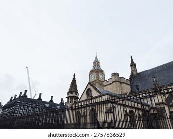 Dramatic low angle view of Big Ben and Gothic Parliament buildings with overcast sky in London, UK.