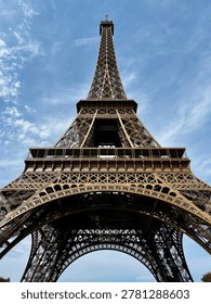Dramatic low angle view of Eiffel Tower in Paris against blue sky, iconic iron architecture and famous French travel landmark