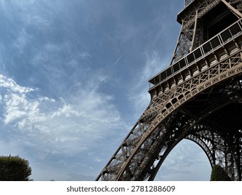 Dramatic low angle view of Eiffel Tower in Paris against blue sky, iconic iron architecture and famous French travel landmark