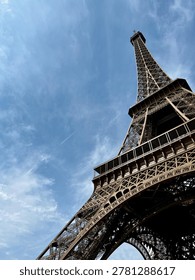 Dramatic low angle view of Eiffel Tower in Paris against blue sky, iconic iron architecture and famous French travel landmark