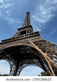 Dramatic low angle view of Eiffel Tower in Paris against blue sky, iconic iron architecture and famous French travel landmark