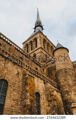 Dramatic Low Angle View Up Mont Saint-Michel Abbey Spire and Weathered Medieval Stone Walls, Normandy France