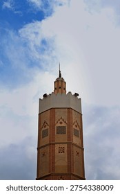 Dramatic Low Angle View of Ornate Minaret Tower Against Blue Sky with Clouds in Asilah, Morocco