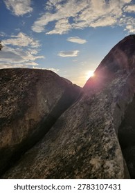 Dramatic low angle view of the sun bursting through a narrow split between large stone boulders 
