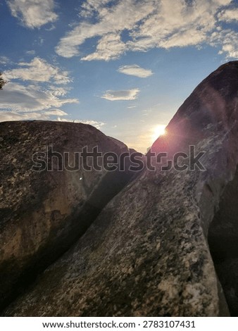 Dramatic low angle view of the sun bursting through a narrow split between large stone boulders 