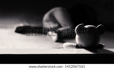 Dramatic low key black and whit of freindship concept.Low key light image of Teddy bear on the bed with sleeping child.Black and white color.