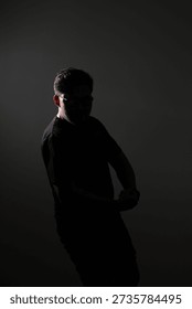 A dramatic, low light portrait of a man captured in silhouette. 