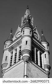 A dramatic low-angle, black and white shot of a towering, ornate clock tower with spires and intricate architectural detail.