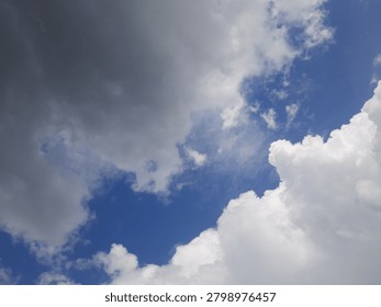 A dramatic low-angle perspective photograph capturing heavy dark rain clouds gathering in a blue sky, signaling an approaching tropical storm or seasonal weather change.