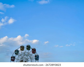 A dramatic low-angle silhouette of a ferris wheel against a cloudy sky at sunset, creating a sense of nostalgia and adventure.