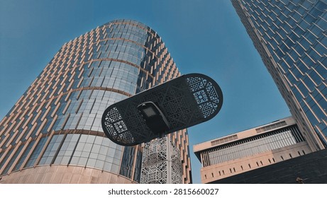Dramatic low-angle upward view of a modern cylindrical glass skyscraper featuring an impressive artistic installation or architectural element in the foreground against a deep blue edited sky. The curved glass facade of the tower creates a striking geometric pattern while the large sculptural element in the foreground adds an interesting compositional contrast between art and architecture. This powerful urban architectural photograph captures the creative intersection of contemporary design and public art in a modern city environment.