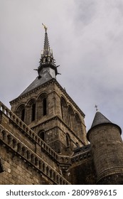 A dramatic low-angle view captures the imposing granite walls and intricate Gothic facade