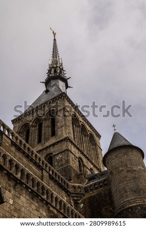 A dramatic low-angle view captures the imposing granite walls and intricate Gothic facade