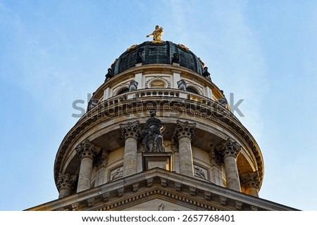Dramatic low-angle view of the grand dome of the Berlin Cathedral (Berliner Dom) in Germany, showcasing its classical columns, ornate details, gleaming golden statue at its apex against clear blue sky