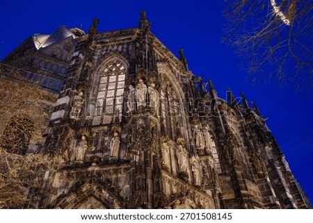 A dramatic, low-angle view of the highly detailed stone facade of a historic Gothic cathedral in Aachen, Germany.