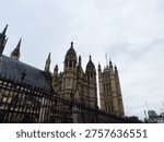 Dramatic low-angle view of the Palace of Westminster and Houses of Parliament under an overcast London sky.
