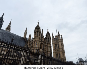 Dramatic low-angle view of the Palace of Westminster and Houses of Parliament under an overcast London sky.