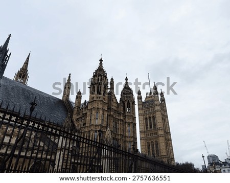Dramatic low-angle view of the Palace of Westminster and Houses of Parliament under an overcast London sky.