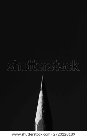 Dramatic low-key macro of a pencil tip emerging from total darkness. Stark lighting highlights the texture of the wood and graphite, ideal for concepts of ideas, inspiration, and mystery.