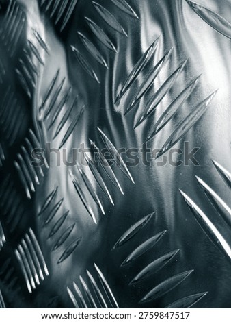 Dramatic macro view of reflective metallic diamond tread plate with sharp highlights