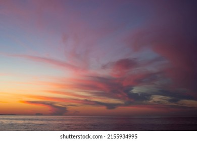 Dramatic majestic clouds in purple pink yellow red shades after sunset in dusk on Lake Baikal, beautiful scenic cloudscape, dark moody style of sundown
