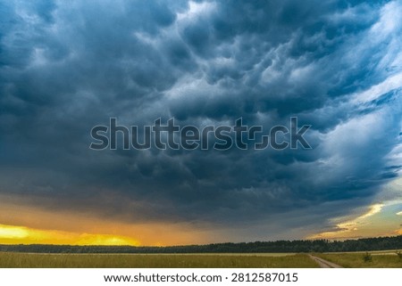 Dramatic Mammatus Storm Clouds over Countryside at Sunset