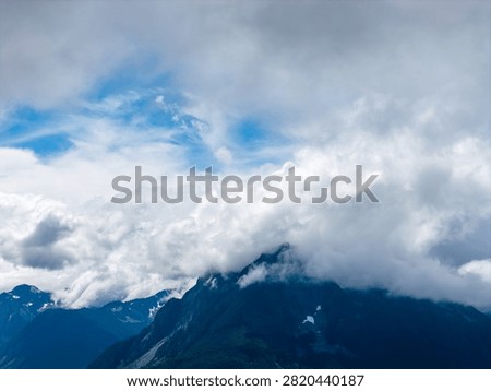 Dramatic mist and layered clouds engulf mountain peaks near Hope, British Columbia, Canada, evoking calm and awe.