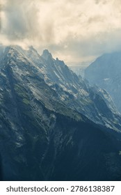 Dramatic mist-shrouded alpine mountain range with jagged peaks and forested valleys