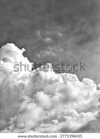 Dramatic monochrome cumulus clouds against a dark, textured sky. This moody, vintage-style atmosphere features high contrast and grainy artistic details, perfect for dramatic backgrounds and fine art.
