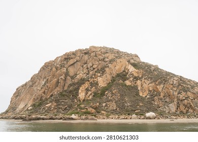 Dramatic Morro Rock Volcanic Plug Shrouded in Cloudy Weather and Coastal Fog, Morro Bay, California
