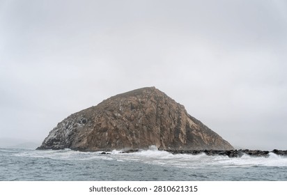 Dramatic Morro Rock Volcanic Plug Shrouded in Cloudy Weather and Coastal Fog, Morro Bay, California