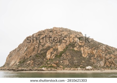 Dramatic Morro Rock Volcanic Plug Shrouded in Cloudy Weather and Coastal Fog, Morro Bay, California