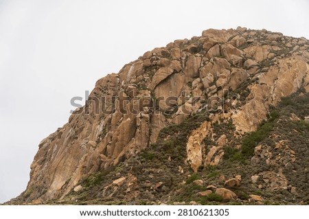 Dramatic Morro Rock Volcanic Plug Shrouded in Cloudy Weather and Coastal Fog, Morro Bay, California