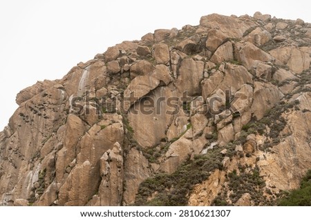Dramatic Morro Rock Volcanic Plug Shrouded in Cloudy Weather and Coastal Fog, Morro Bay, California