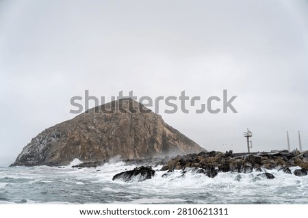 Dramatic Morro Rock Volcanic Plug Shrouded in Cloudy Weather and Coastal Fog, Morro Bay, California