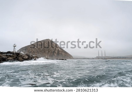 Dramatic Morro Rock Volcanic Plug Shrouded in Cloudy Weather and Coastal Fog, Morro Bay, California
