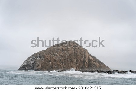 Dramatic Morro Rock Volcanic Plug Shrouded in Cloudy Weather and Coastal Fog, Morro Bay, California