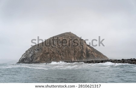 Dramatic Morro Rock Volcanic Plug Shrouded in Cloudy Weather and Coastal Fog, Morro Bay, California