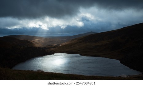 Dramatic Mountain Landscape with Dark Clouds and Reflected Light Over Serene Lake