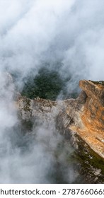 Dramatic mountain landscape featuring Pedra do Baú rising above dense fog and low clouds in the Serra da Mantiqueira region of southeastern Brazil. The massive rock formation dominates the scenery with steep walls and rugged terrain surrounded by forested hills and elevated peaks. Soft diffused light filters through mist covering the mountains, creating a cinematic atmosphere associated with adventure, exploration and remote highland environments.

The location is widely recognized for climbing, hiking and mountaineering activities, attracting visitors seeking outdoor experiences and panoramic views above the clouds. Trails crossing the mountainsides reveal changing weather conditions typical of high elevation regions, where fog and moving clouds constantly transform the scenery. The combination of dramatic relief, natural textures and expansive horizons creates a visually striking environment connected with ecotourism and adventure travel.

This scene was photographed at Pedra do Baú in the Serra da Mantiqueira, a famous destination in Brazil admired for rock climbing routes, mountain landscapes and scenic viewpoints surrounded by preserved nature in South America.